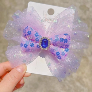 Sparkly purple princess bow hair clip with blue gemstone and glitter mesh detail
