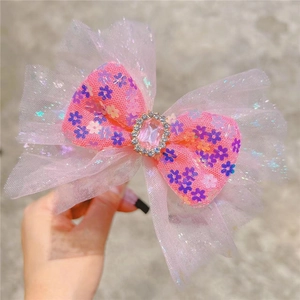 Close-up of pink sequin mesh bow hair clip with central pink gemstone and crystal details