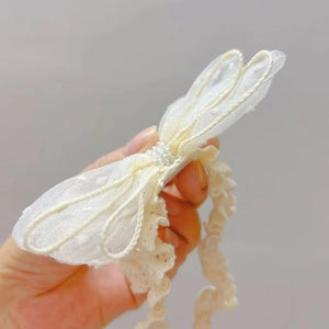 Detailansicht Baby-Stirnband mit Spitzen-Schleife, Perlenverzierung und weicher Textur