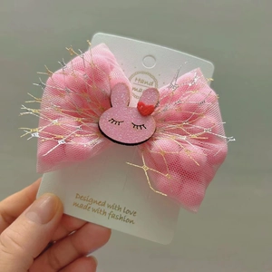 Detail of handmade pink tulle bow hair clip with a cute rabbit and heart charm on card