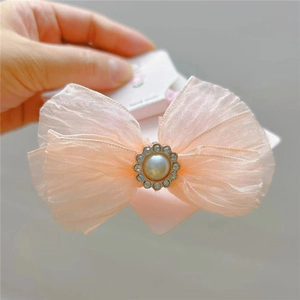 Detail of pink tulle bow hair clip with faux pearl and crystal rhinestones center