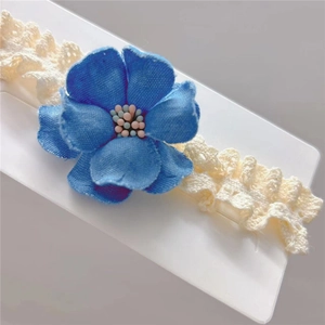 Détail d'une fleur de camélia bleue et d'un bandeau en dentelle blanche pour bébés