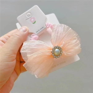 Detail of pink mesh bow hair tie featuring faux pearls and rhinestones decoration