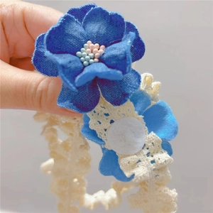 Détail du bandeau en dentelle pour bébé avec camélia bleu et centre perlé décoratif