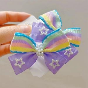 Detail of sweet purple bow hair clip with rainbow stripes and imitation pearl accents