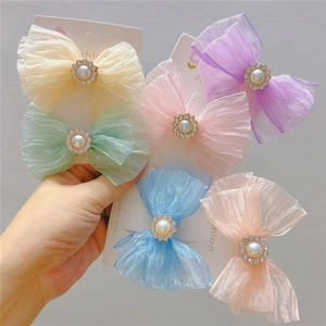 Close-up of mesh bow hair clips with pearls and rhinestones in macaron colors