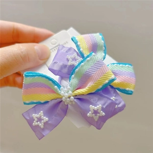 Detailed view of rainbow striped bow hair tie with purple mesh and pearl star accents
