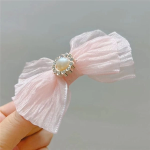 Close-up of pink tulle bow hair clip with central pearl and sparkling crystal accents