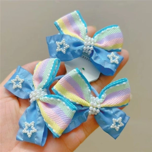 Detail of light blue bow hair clips with white pearls and rainbow striped fabric texture
