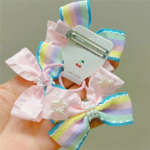 Close-up of pink ribbon hair bow clip and tie with striped edges and pearl star detail
