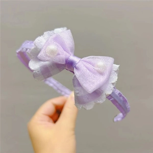 Dettaglio cerchietto viola con fiocco, pizzo e accenti di perle per bambine
