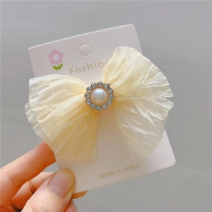 Close-up of cream mesh bow hair clip with faux pearl and rhinestone details