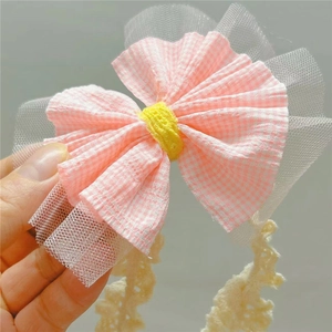 Gros plan sur un nœud à carreaux roses avec dentelle en tulle et longs rubans au crochet