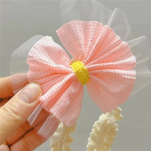 Gros plan du bandeau avec nœud rose à carreaux et détails en tulle pour les bébés