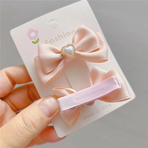 Detail von rosa Satin-Haarschleifen mit Herzperle und bandumwickelter Metallrückseite
