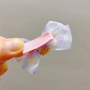 Détail de la barrette à nœud violet à pois avec couronne dorée sur pince ruban rose