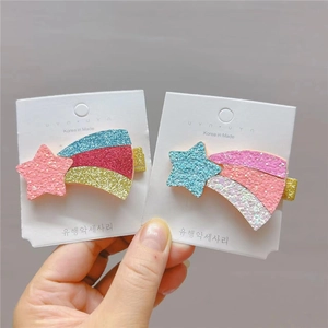 Detail of glitter star hair clips with colorful rainbow tails on a display card