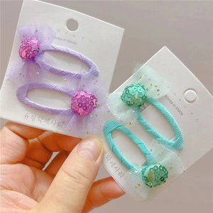 Détail de pinces à cheveux avec nœuds à paillettes violettes et vert menthe pour filles