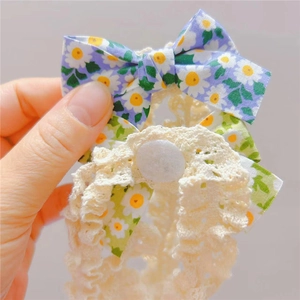 Détail du bandeau à nœud floral avec imprimé marguerites sur tissu violet et vert et dentelle