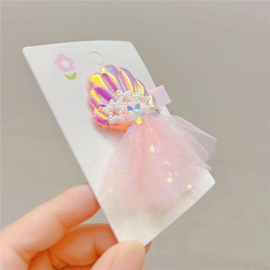 Detail of pink laser shell hair clip with pearls and sequin mesh skirt for beach theme