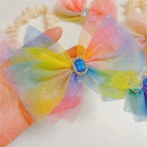 Detail showing the rainbow gradient mesh bow with a central blue gemstone and rhinestones