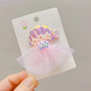Close-up of a laser shell hair clip with pink mesh tulle and star-shaped pearls
