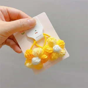 Nahaufnahme von handgehäkelten Gänseblümchen-Haargummis mit gelben Gummibändern
