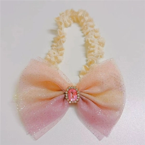 Close-up of a gradient mesh bow headband with a pink gemstone for infants
