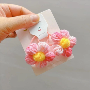 Detail von handgehäkelten Blumen-Haargummis in Rosa und Gelb auf Karte