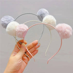 Détail d'un ensemble de trois serre-têtes à pompons en peluche douce pour filles