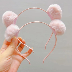 Gros plan de serre-têtes à pompons roses doux pour filles avec texture pelucheuse