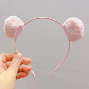 Détail des pompons roses moelleux et du tissu texturé sur le serre-tête pour enfants