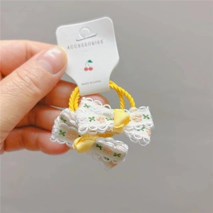 Dettaglio di elastici per capelli gialli con motivi di ciliegie e bordi in pizzo