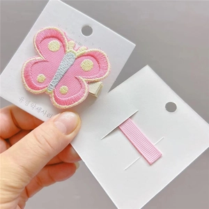 Détail de la pince à cheveux papillon brodée rose avec une base en métal de qualité