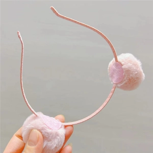 Détail de pompons en fausse fourrure rose sur un serre-tête fin pour petite fille