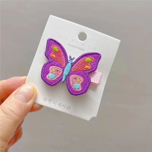 Barrette à cheveux papillon brodée avec motifs colorés sur une carte de présentation