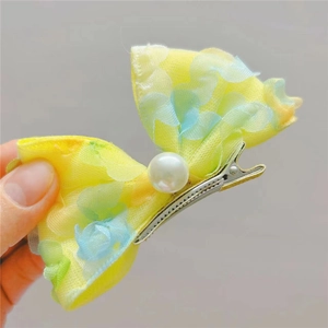 Détail d'une barrette nœud jaune avec pétales en tulle, perle et pince crocodile en métal