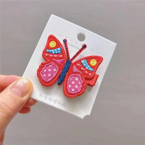 Gros plan sur la pince à cheveux papillon rouge brodée avec des motifs colorés