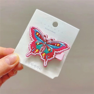 Détail de la pince à cheveux papillon brodée colorée sur carte de présentation avec broderie