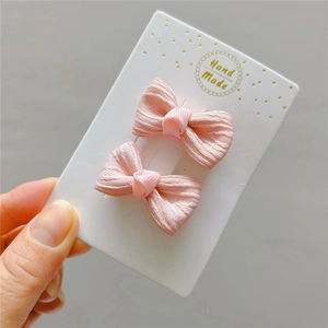 Dettaglio di fermagli per capelli con fiocco rosa in tessuto a coste su cartoncino
