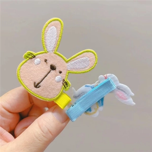 Detail of embroidered bunny hair clip with yellow border and blue wrapped safety clip