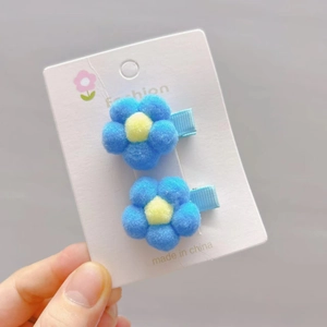 Close-up of sky blue plush flower hair clips for girls on a white fashion card