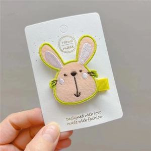 Cute pink embroidered bunny hair clip with yellow ribbon on a white card