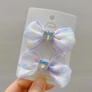 Detail van twee chiffon strikken met polkadots en strass hartjes op displaykaart