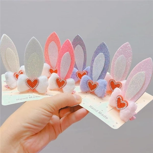 Close-up of plush bow hair clips with glitter rabbit ears and sparkling heart rhinestones