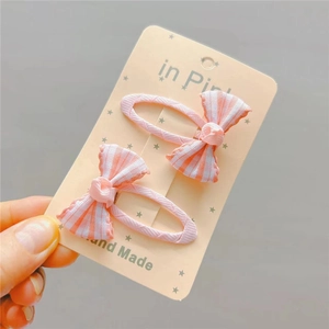 Set of two pink plaid bow hair clips for girls on a decorative display card