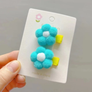 Close-up of handmade plush flower hair clips with soft blue petals and yellow ribbon base