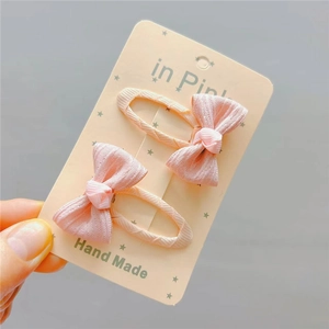 Close-up of handmade pink fabric plaid bow hair clips with soft textile texture