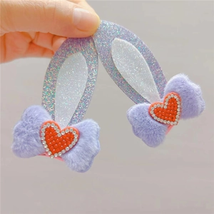 Macro shot of purple glitter rabbit ears hair clips with plush bows and red heart rhinestones