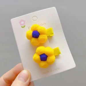 Detailed view of yellow plush flower hair clips on a white presentation card